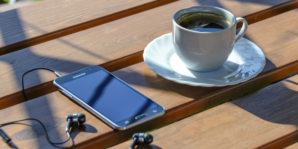 テーブルに置かれたスマートフォンとコーヒー